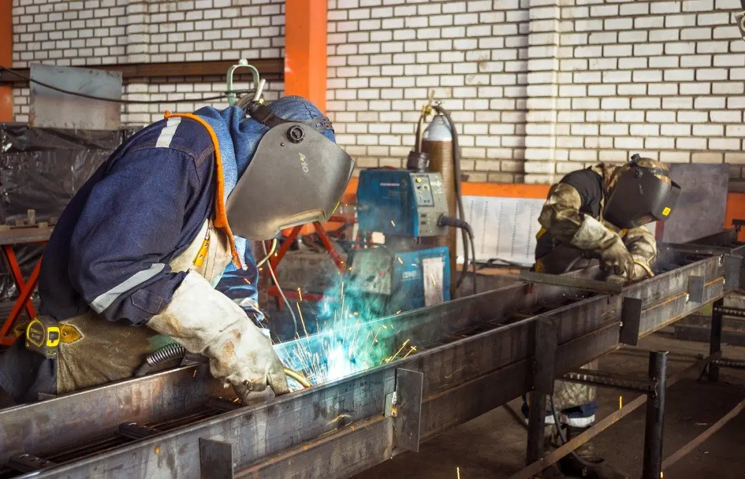 Fabricators welding steel sections in a workshop